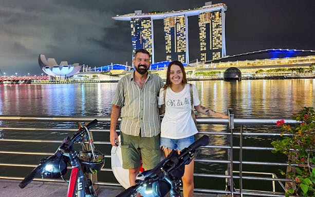 Couple posing with bikes at Marina Bay Sands during night bike tour in Singapore.