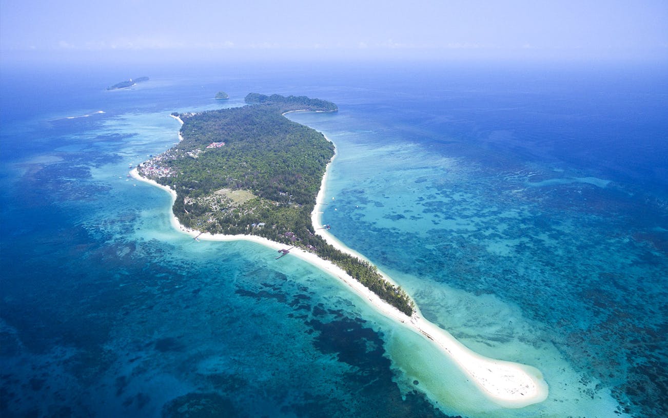 Aerial view of a tropical island with lush greenery and turquoise waters, near Kawa Kawa River.