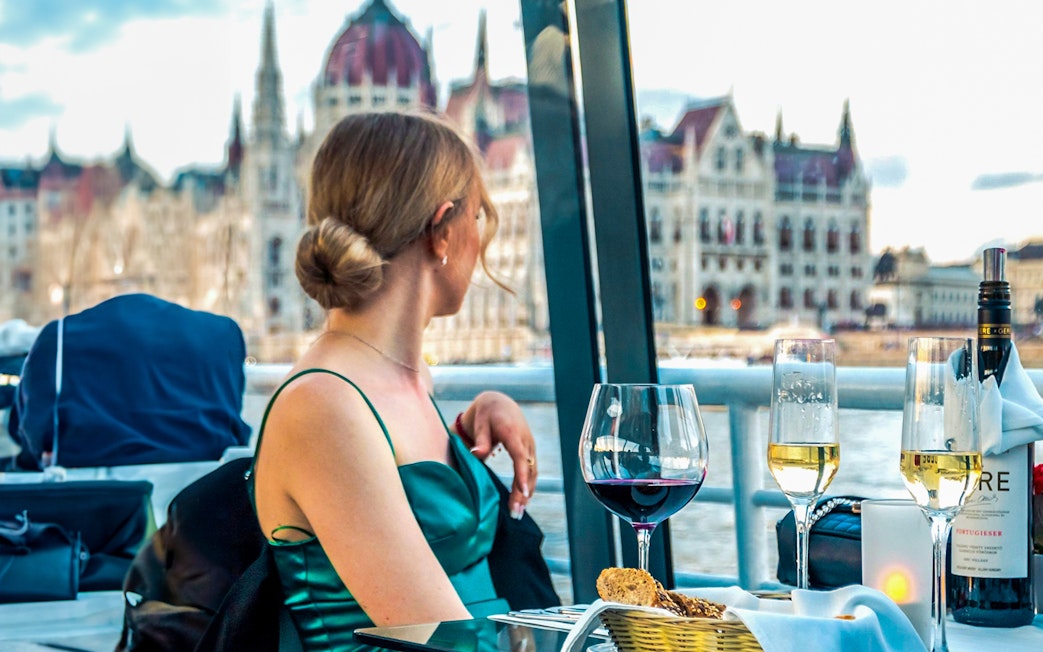 Guest enjoying wine on Budapest Candlelit Dinner Cruise with Parliament view.