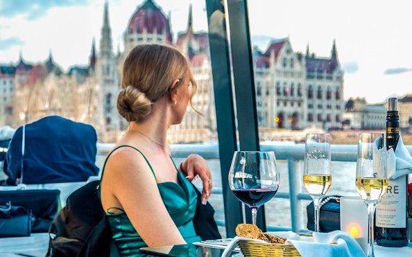 Guest enjoying wine on Budapest Candlelit Dinner Cruise with Parliament view.