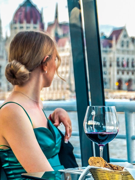 Guest enjoying wine on Budapest Candlelit Dinner Cruise with Parliament view.