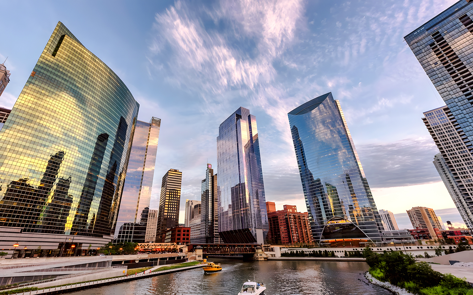 Chicago skyline with modern skyscrapers reflecting sunset colors over the river.
