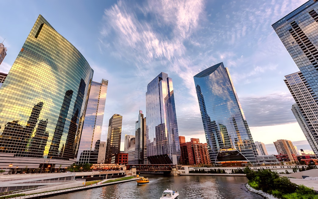 Chicago skyline with modern skyscrapers reflecting sunset colors over the river.