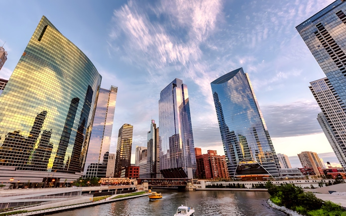 Chicago skyline with modern skyscrapers reflecting sunset colors over the river.