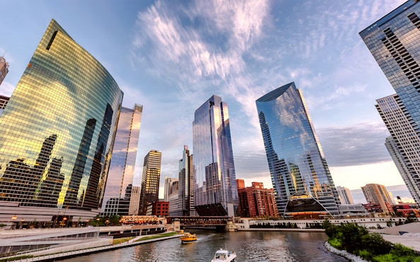 Chicago skyline with modern skyscrapers reflecting sunset colors over the river.