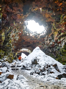Guests exploring snow-covered Raufarhólshellir Lava Cave, Iceland.