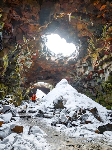 Guests exploring snow-covered Raufarhólshellir Lava Cave, Iceland.