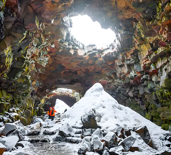 Guests exploring snow-covered Raufarhólshellir Lava Cave, Iceland.