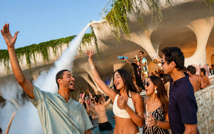 People enjoying a lively pool party at Luna Beach Club with drinks and music.