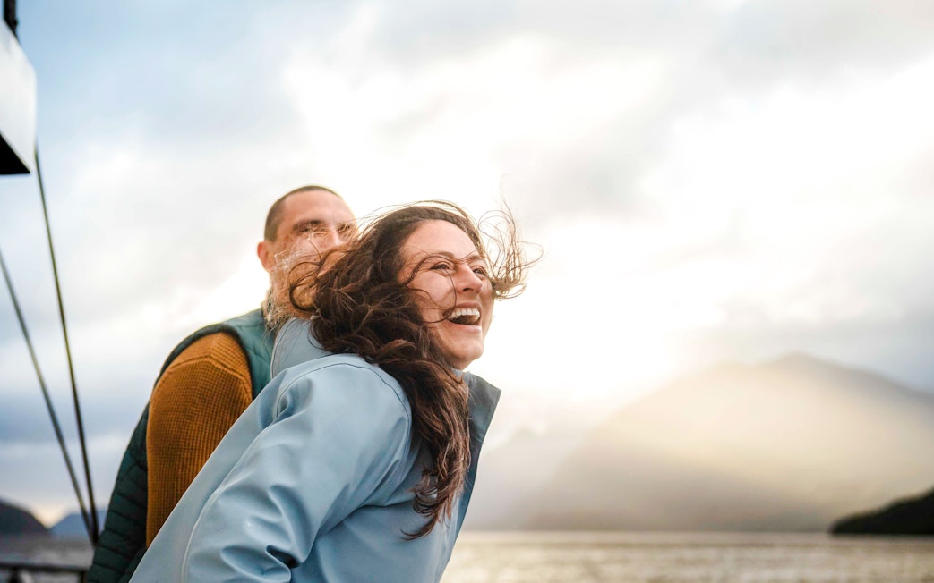 Woman laughing on boat deck during Doubtful Sound Wilderness Cruise, New Zealand.