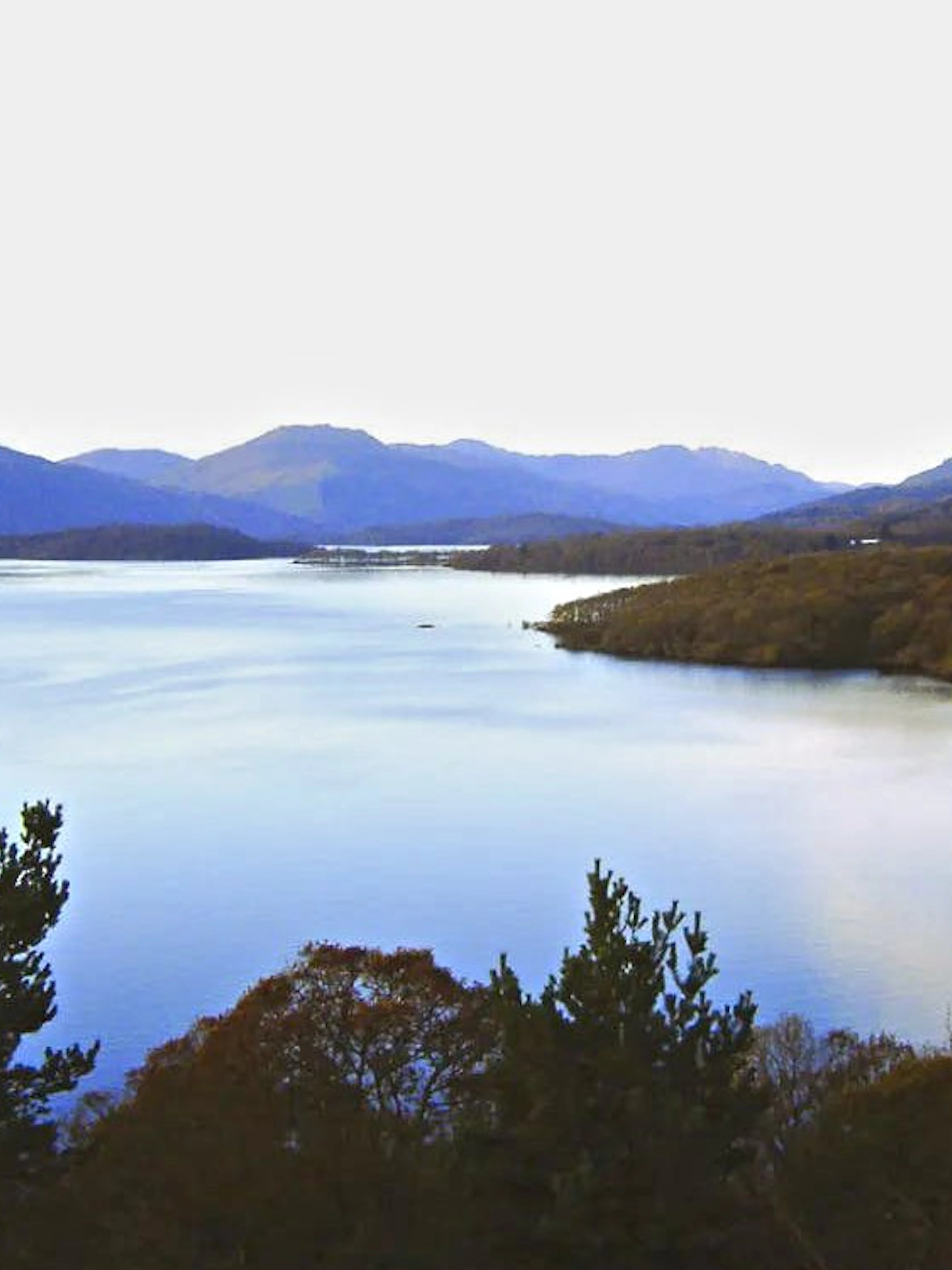 Loch Lomond view with surrounding hills and trees in Scotland.