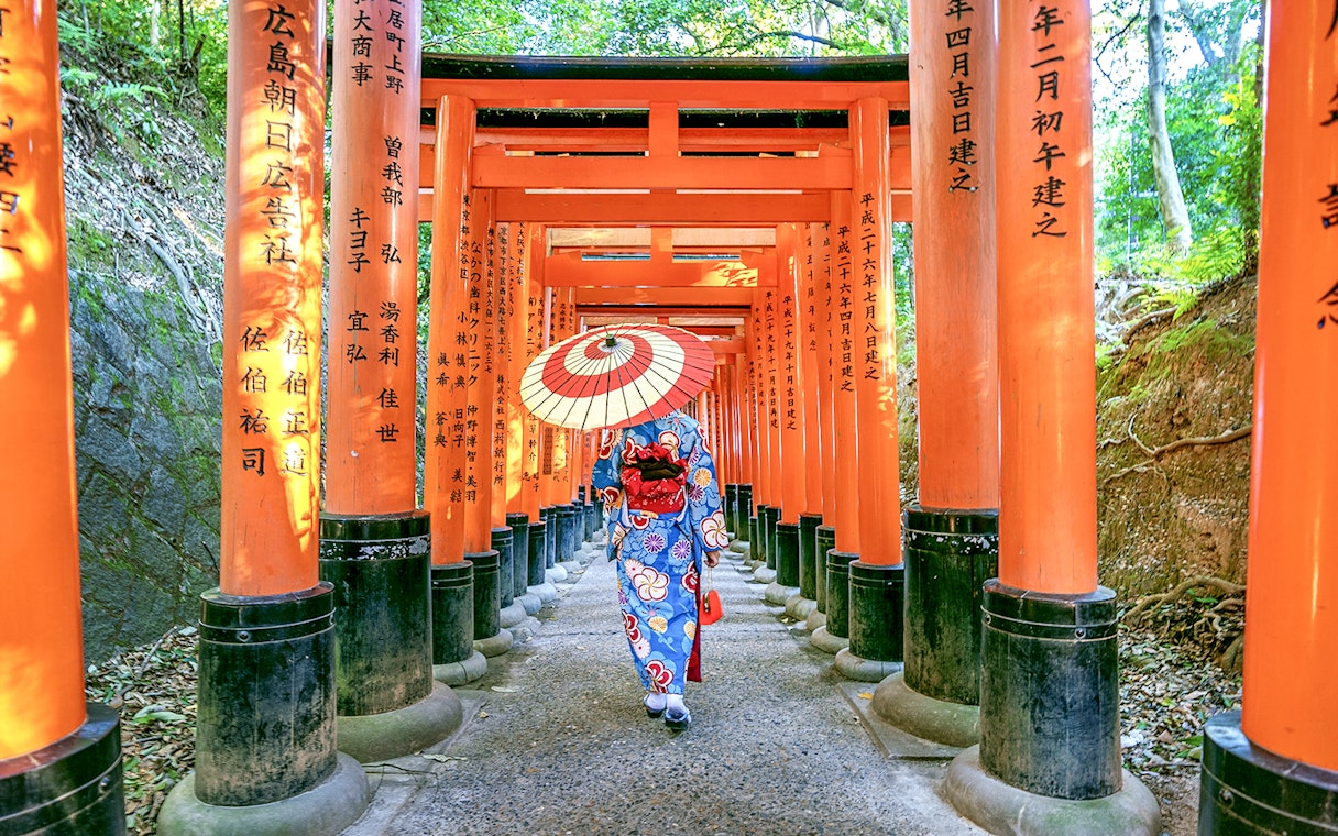 Person in kimono walking through Fushimi Inari Shrine's torii gates, Kyoto.
