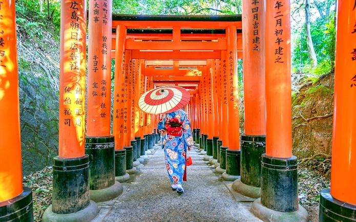 Person in kimono walking through Fushimi Inari Shrine's torii gates, Kyoto.