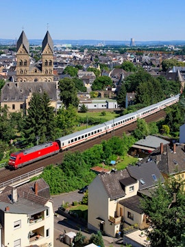 Train passing through a European town with historic church towers, highlighting Global Interrail Passes.