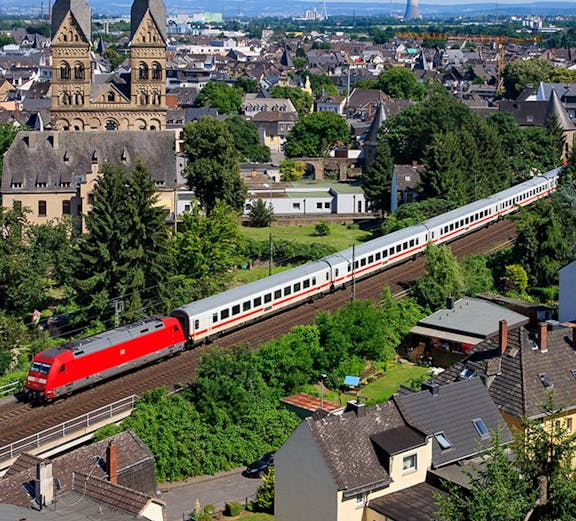 Train passing through a European town with historic church towers, highlighting Global Interrail Passes.