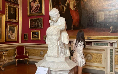 Sculpture of a child in Pitti Palace exhibition room with paintings.