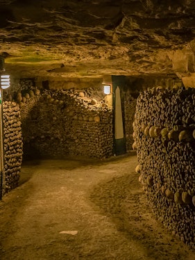Paris Catacombs tunnel with walls of arranged skulls and bones.