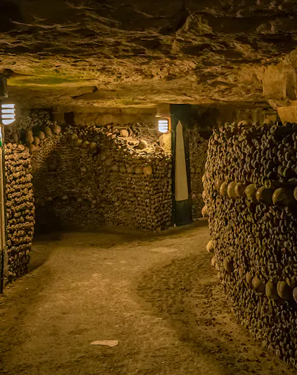 Paris Catacombs tunnel with walls of arranged skulls and bones.