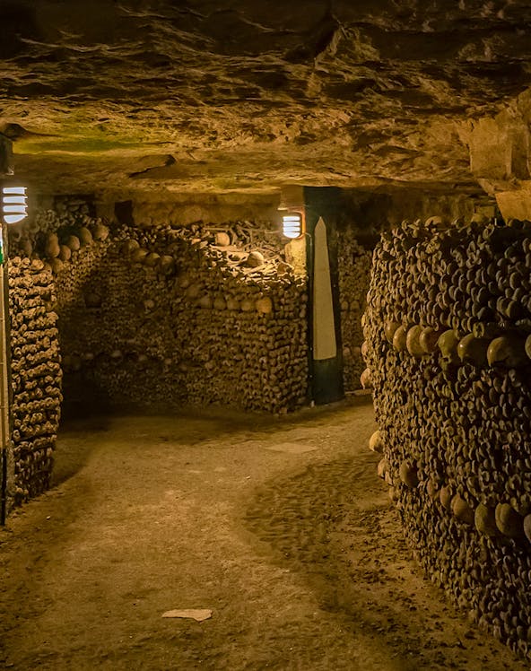 Paris Catacombs tunnel with walls of arranged skulls and bones.