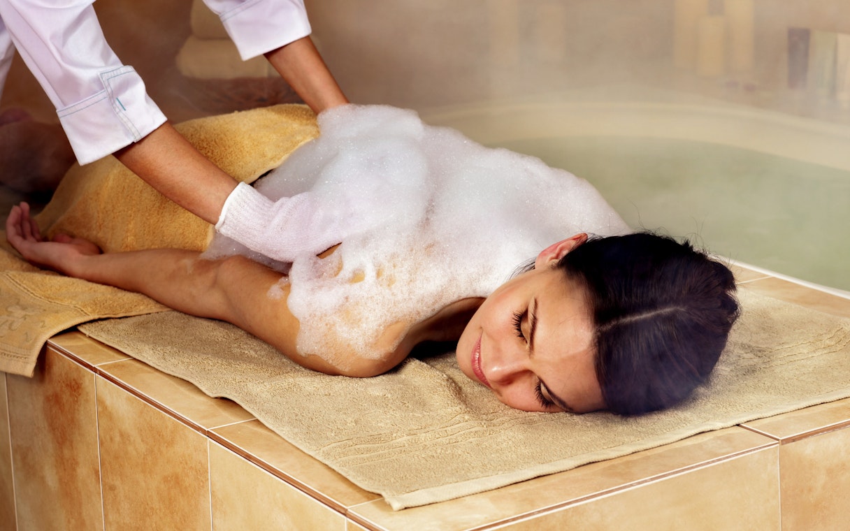 Woman receiving foam massage at a Turkish bathhouse spa.