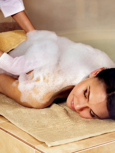 Woman receiving foam massage at a Turkish bathhouse spa.
