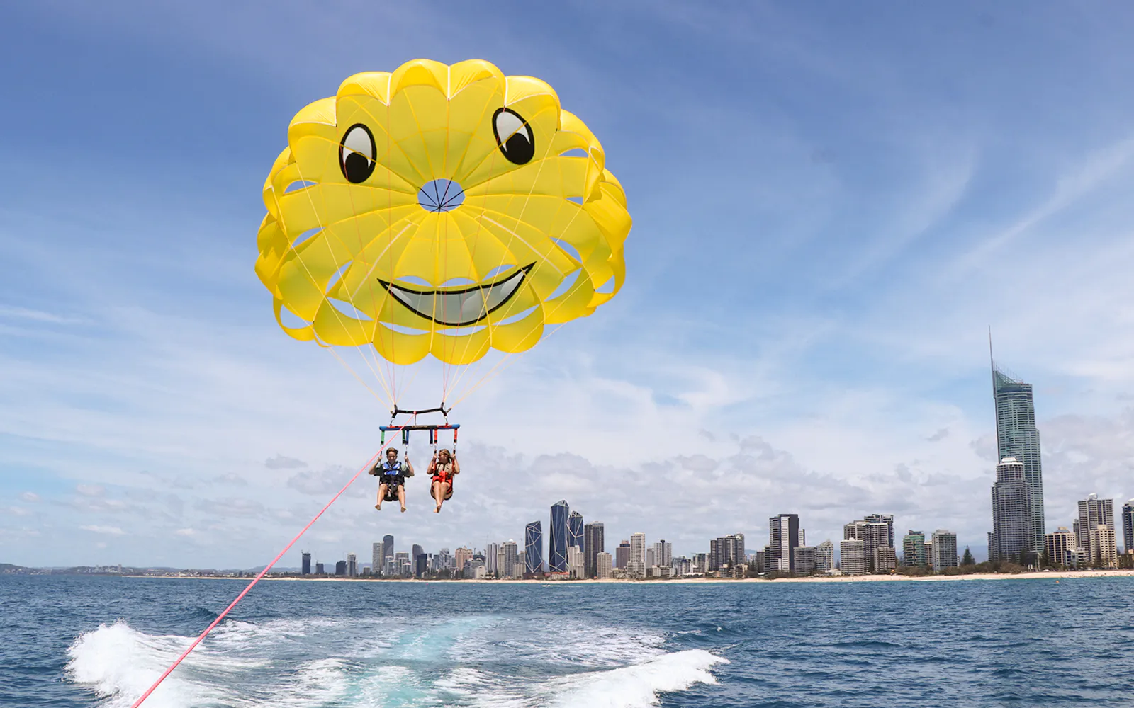 Parasailing over ocean with city skyline in background, Jet Ski & Parasail Experience.