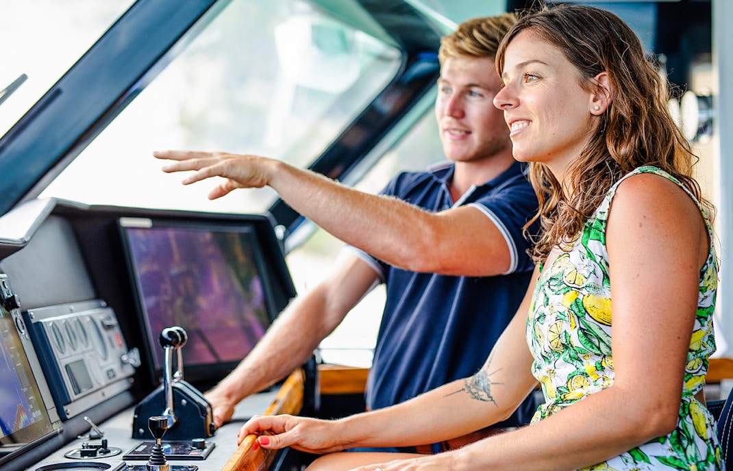 Tour guide explaining boat controls to a visitor at Moreton Island.