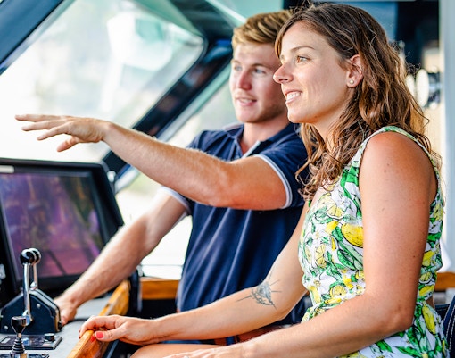 Tour guide explaining boat controls to a visitor at Moreton Island.