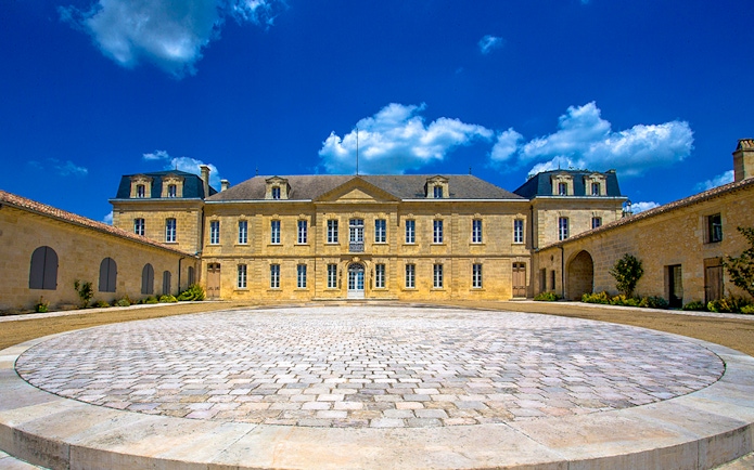 Saint Emilion winery courtyard with historic building under blue sky.