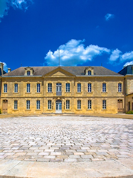 Saint Emilion winery courtyard with historic building under blue sky.