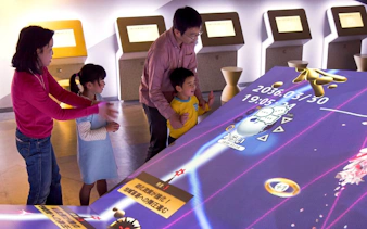 Visitors interacting with a digital exhibit at Miraikan, Tokyo's science museum.
