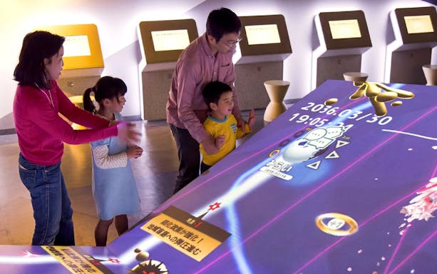 Visitors interacting with a digital exhibit at Miraikan, Tokyo's science museum.