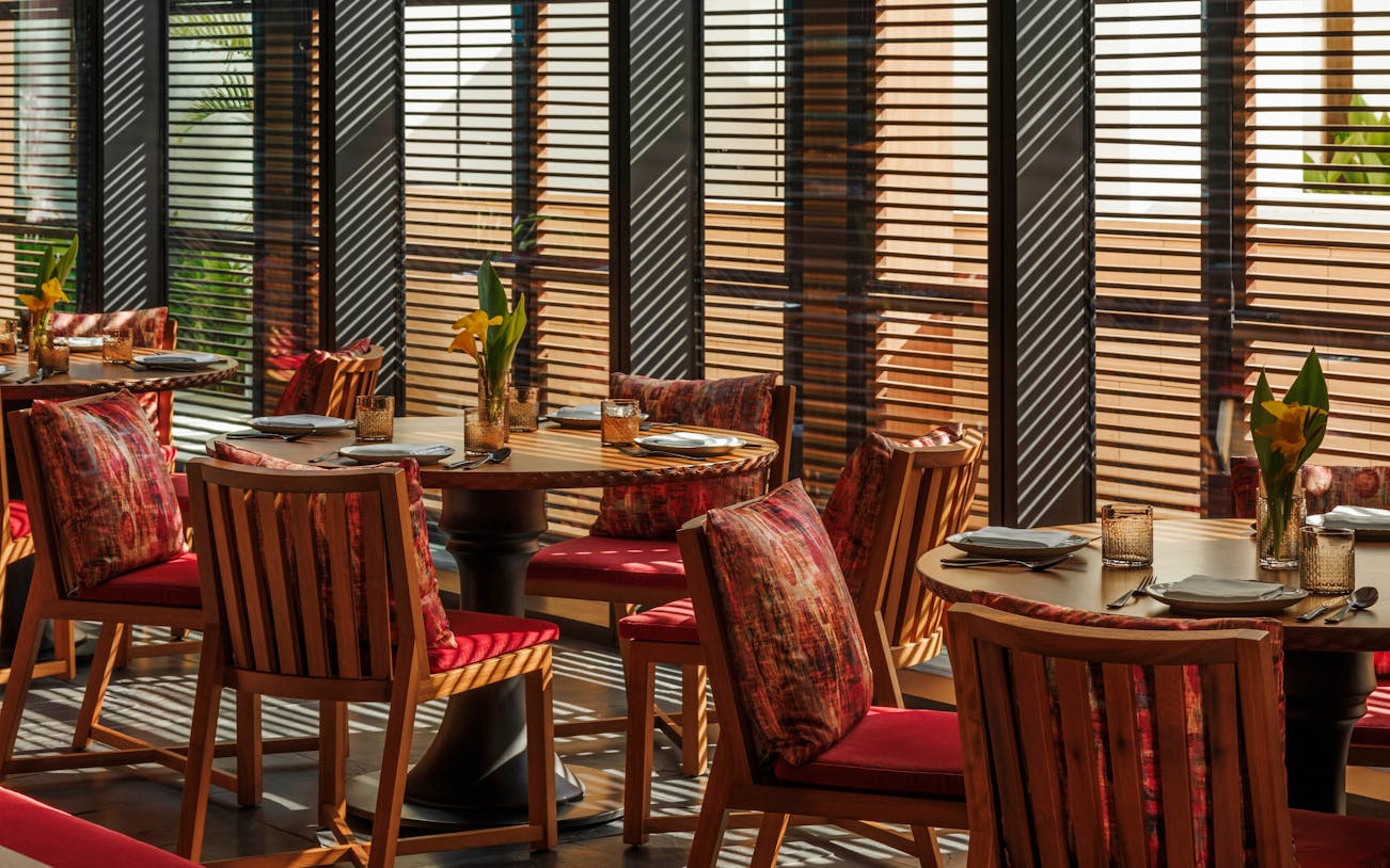 Dining tables set for Sunday Brunch at Andaliman, Dubai with sunlight filtering through blinds.