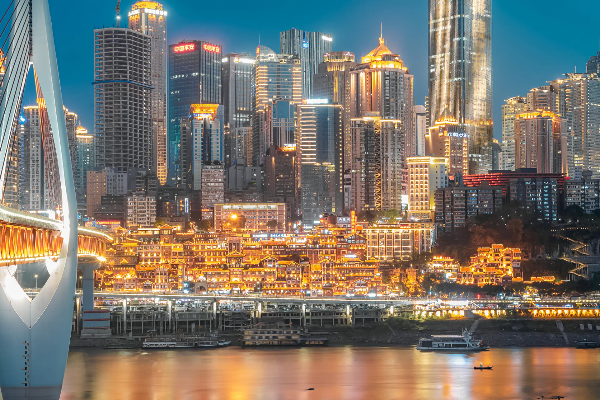 Chongqing skyline at night with illuminated skyscrapers and bridge over the Yangtze River.