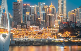 Chongqing skyline at night with illuminated skyscrapers and bridge over the Yangtze River.
