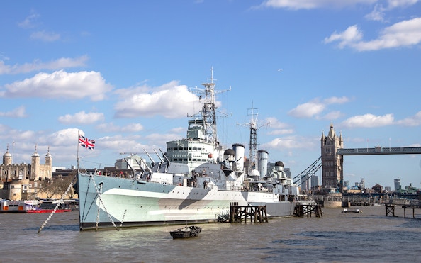 HMS Belfast moored on the River Thames with Tower Bridge in the background, London.