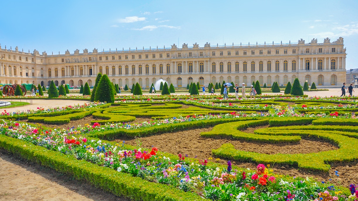 Palace of Versailles with vibrant flower garden in foreground, France.