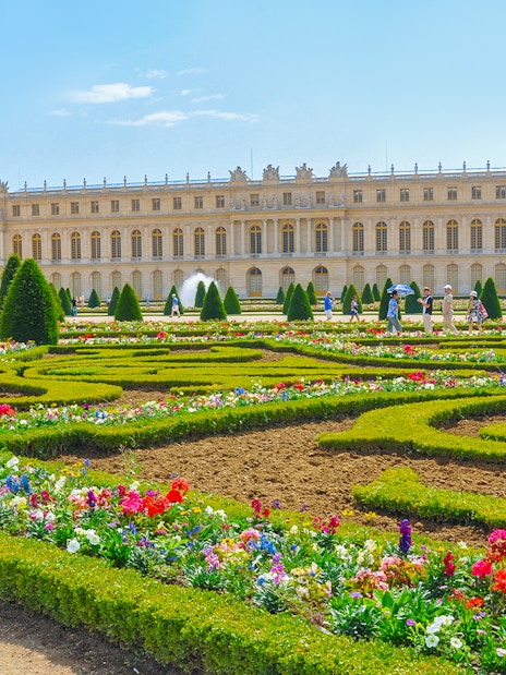 Palace of Versailles with vibrant flower garden in foreground, France.
