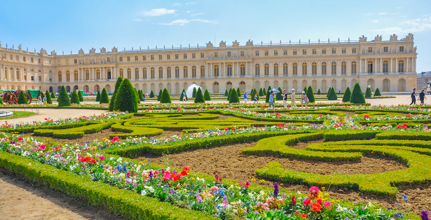 Palace of Versailles with vibrant flower garden in foreground, France.