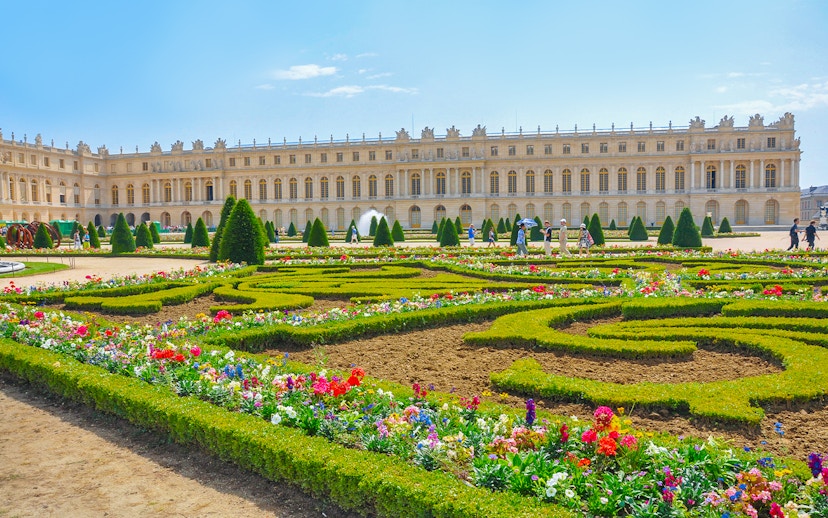Palace of Versailles with vibrant flower garden in foreground, France.