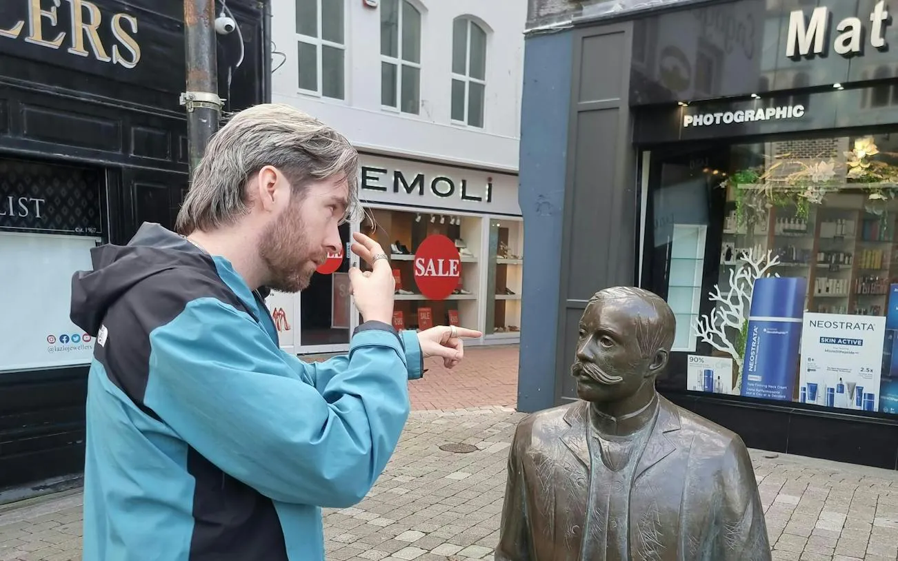 Man interacting with a statue on a Galway street during a self-guided city exploration game.