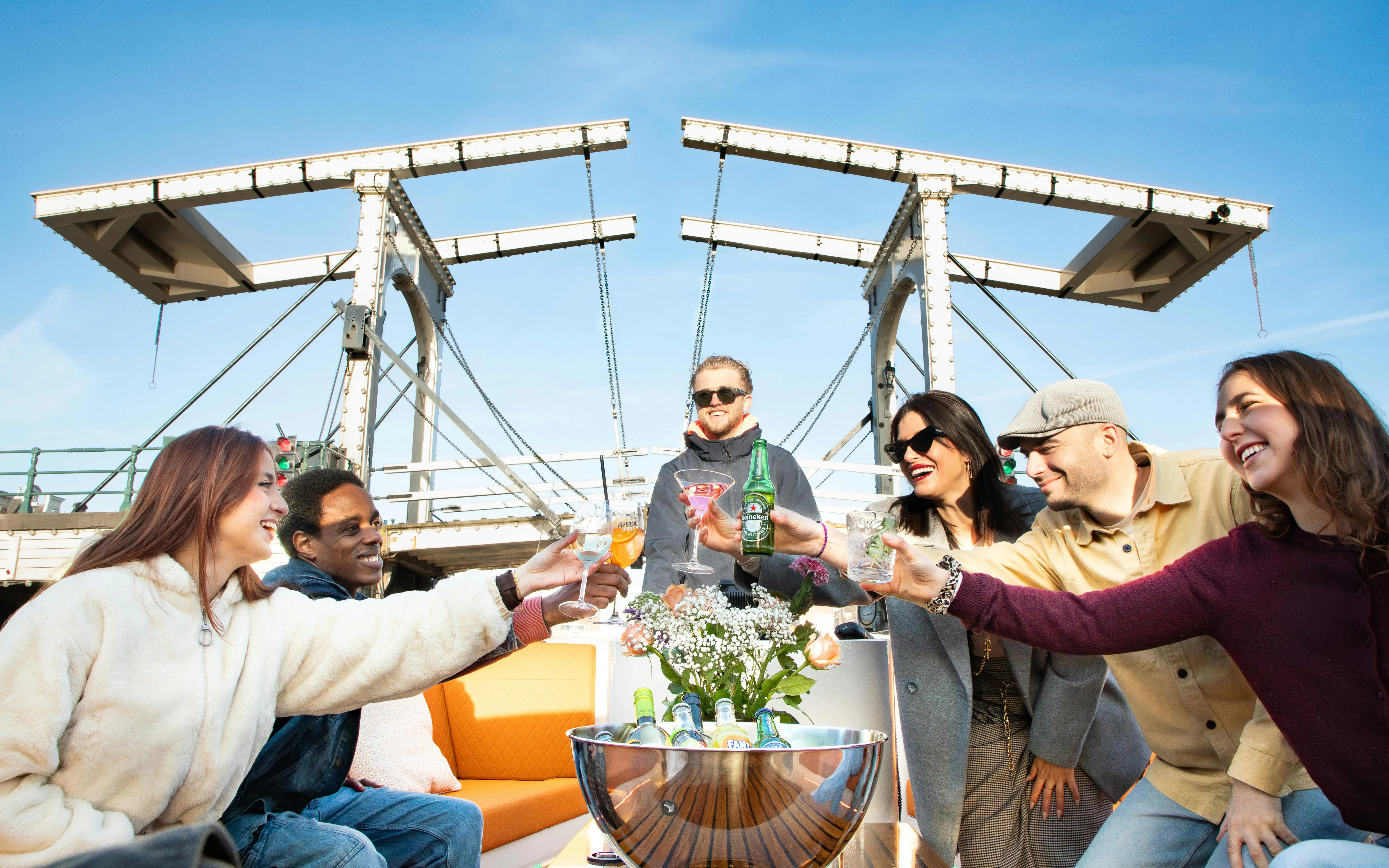 Group enjoying drinks on a luxury boat cruise under Amsterdam's Magere Brug.