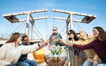 Group enjoying drinks on a luxury boat cruise under Amsterdam's Magere Brug.