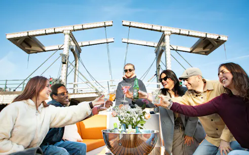 Group enjoying drinks on a luxury boat cruise under Amsterdam's Magere Brug.