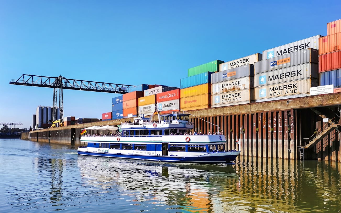 Cruise boat on Rhine River near Cologne container port.