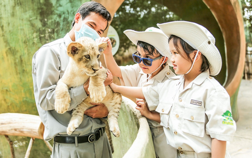 Children petting a lion cub at Vinpearl Safari.