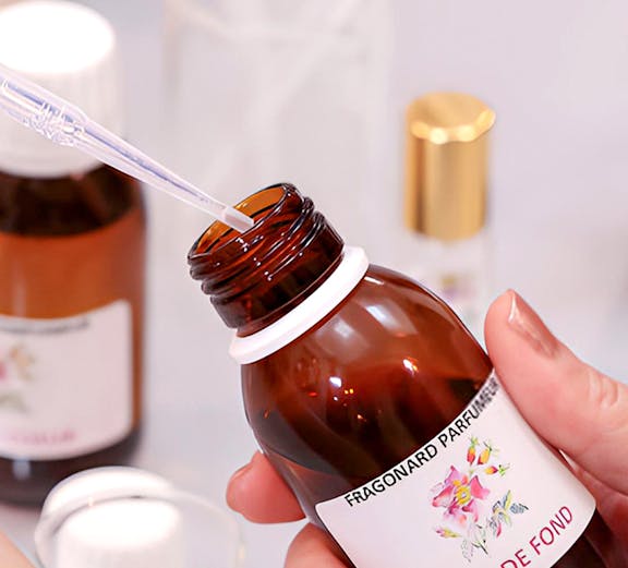 Fragonard Perfume Museum visitor holding a fragrance bottle with pipette.