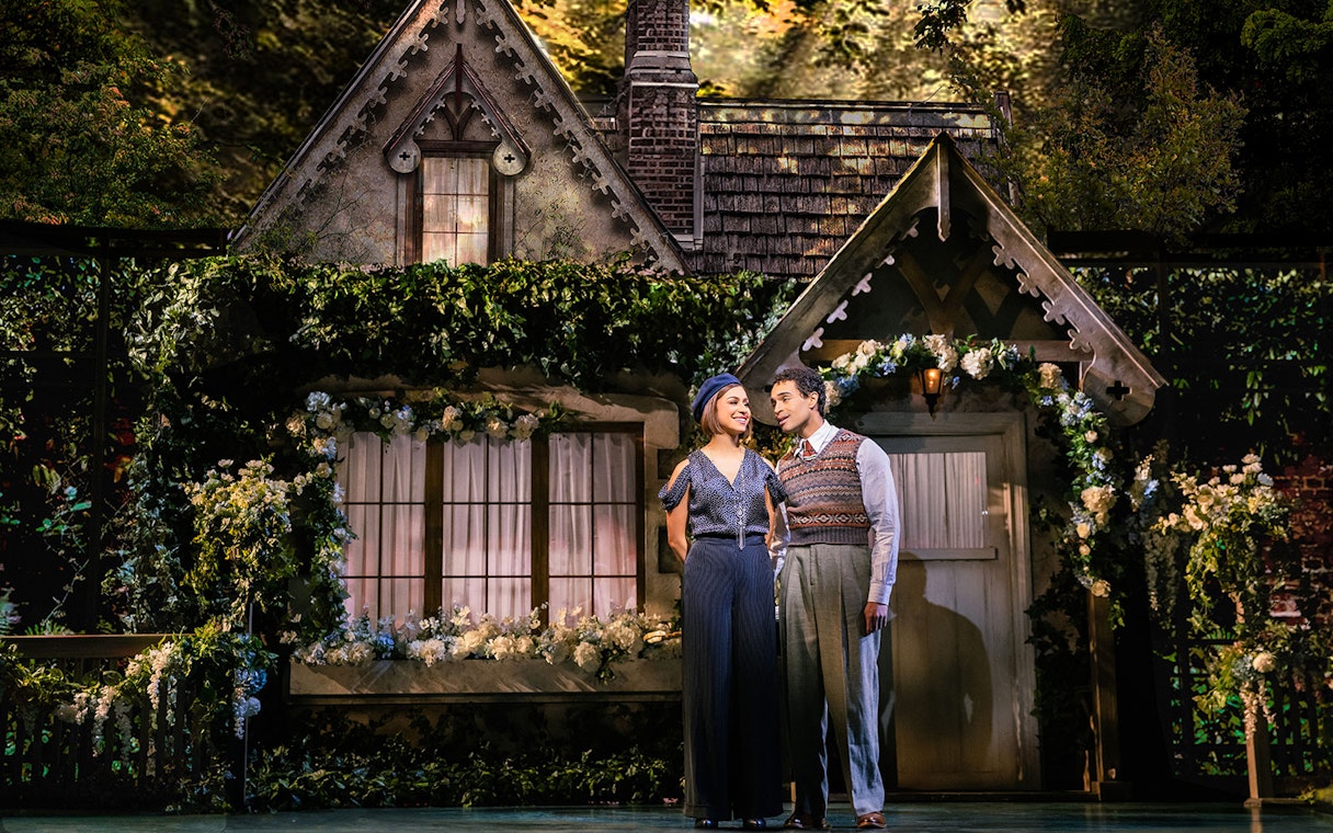 Couple standing in front of a cottage set during a theatrical performance of The Great Gatsby.