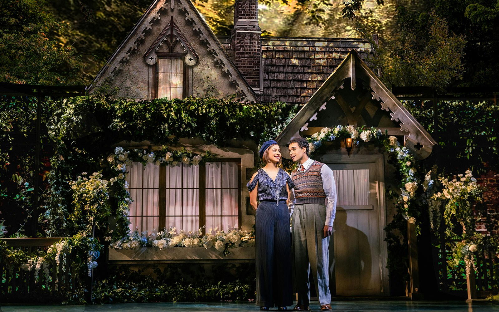 Couple standing in front of a cottage set during a theatrical performance of The Great Gatsby.