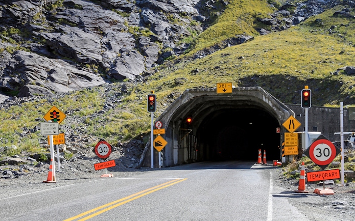 Entrance to Homer Tunnel with traffic signs on the road to Milford Sound, Fiordland National Park, New Zealand.